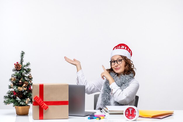 Front view young female worker sitting before her working place on white background