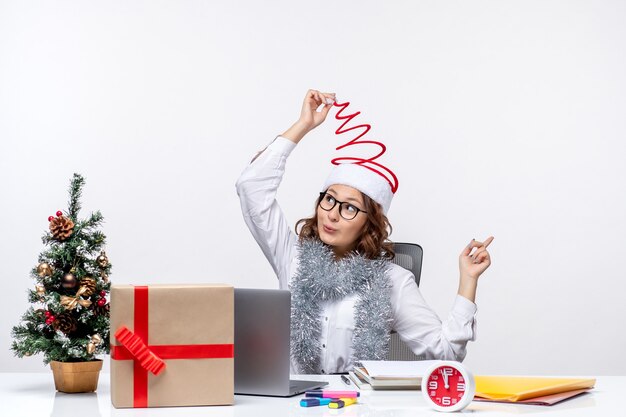 Front view young female worker sitting before her working place on white background