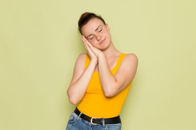 A front view young female in yellow shirt and blue jeans with sleeping pose