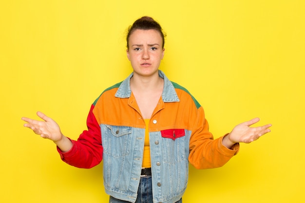 Foto gratuita una giovane donna vista frontale in giacca colorata camicia gialla e blue jeans con espressione scontenta