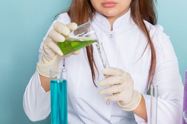 Free photo front view of young feman chemist in white suit in front of table working with solutions