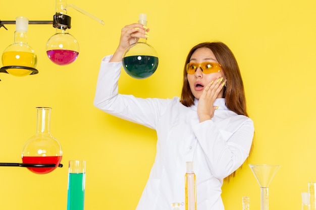 Front view of young feman chemist in white suit in front of table working with solutions