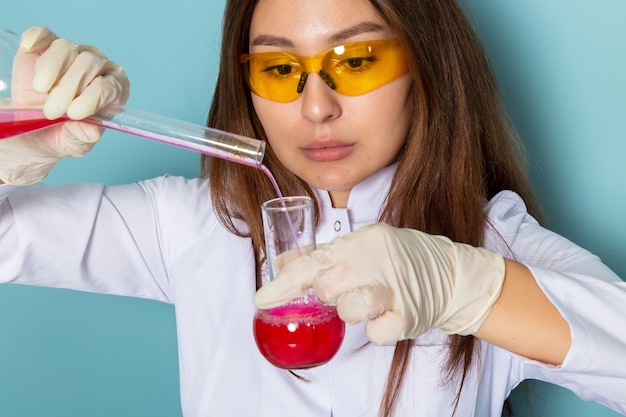 Front view of young feman chemist in white suit working