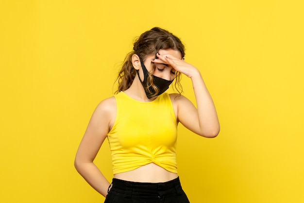 Front view of young girl having head pain on yellow wall