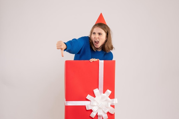 Front view of young girl inside red present box on the white wall