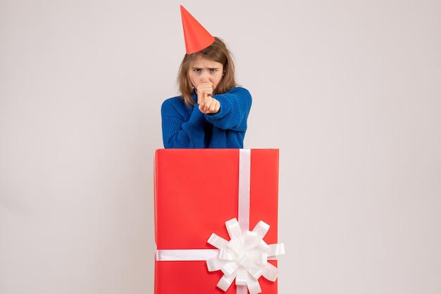 Front view of young girl inside red present box on white wall