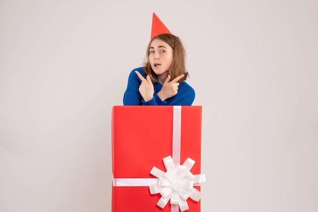 Front view of young girl inside red present box on white wall