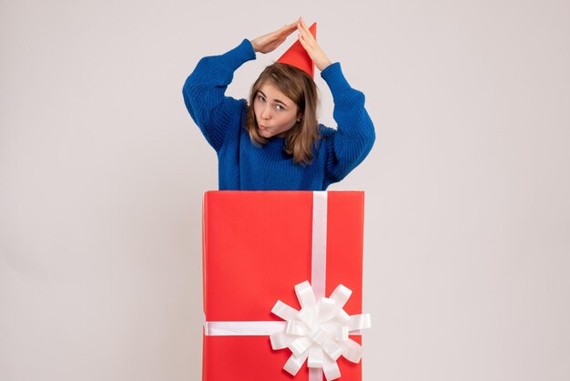 Front view of young girl inside red present box on white wall