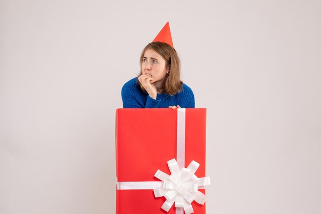 Front view of young girl inside red present box on white wall