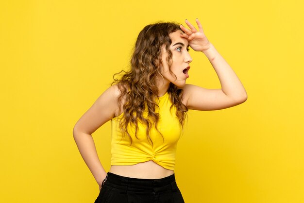 Front view of young girl looking at distance on a yellow wall
