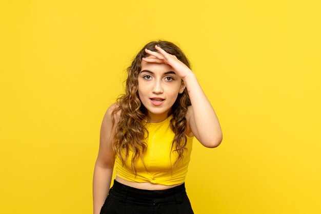 Front view of young girl looking at distance on yellow wall