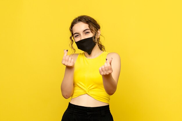 Front view of young girl in mask on yellow wall