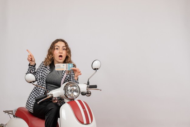 Front view young girl on moped holding ticket pointing at left