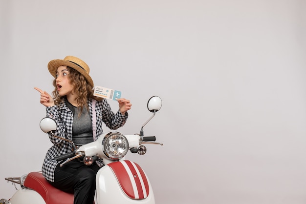 Front view young girl on moped holding up ticket pointing at left