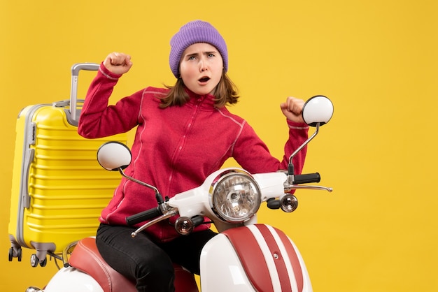 Front view young girl on moped showing winning gesture