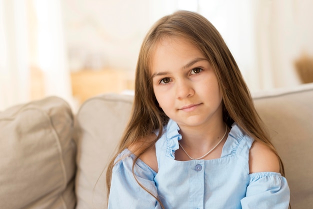 Front view of young girl posing at home on the couch