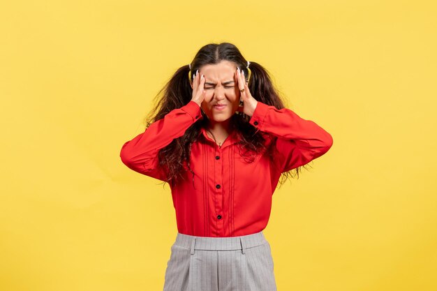 Front view young girl in red blouse with cute hair suffering from headache on yellow background child color kid girl youth innocence