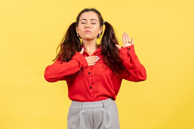 Front view young girl in red blouse with dreaming expression on yellow background female feeling child kid girl youth emotion