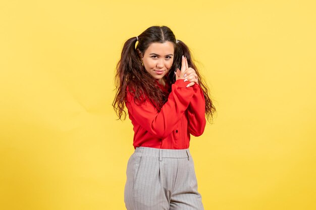 Front view young girl in red blouse with gun holding pose on yellow background innocence child youth kid girl female