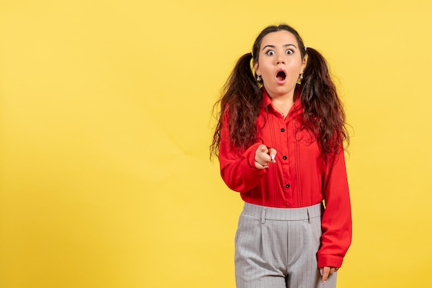 Foto gratuita vista frontale ragazza in camicetta rossa con faccia sorpresa su sfondo giallo colore innocenza bambino ragazza gioventù ragazzo