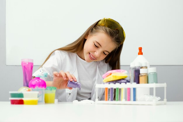 Front view of young girl scientist experimenting with slime and colors