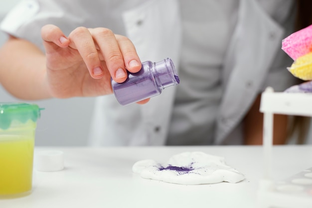 Front view of young girl scientist experimenting with slime and pigments