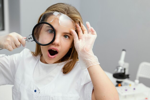 Front view of young girl scientist using magnifying glass