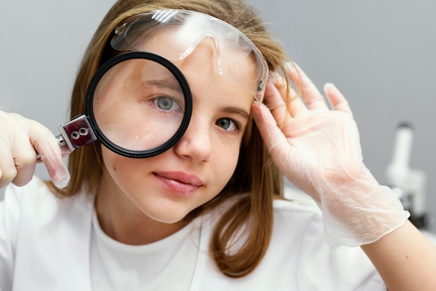 Front view of young girl scientist with magnifying glass