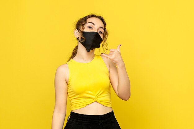 Front view of young girl in sterile mask on yellow wall