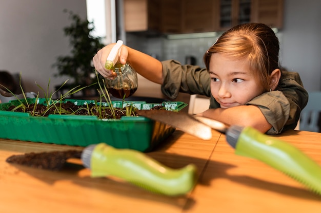 Front view of young girl watering crops at home