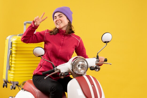 Front view young girl with blinked eye on moped gesturing victory sign