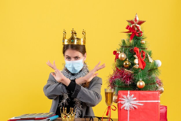 그녀의 손에 크리스마스 트리와 선물 칵테일을 건너 왕관을 쓰고 의료 마스크와 전면보기 어린 소녀