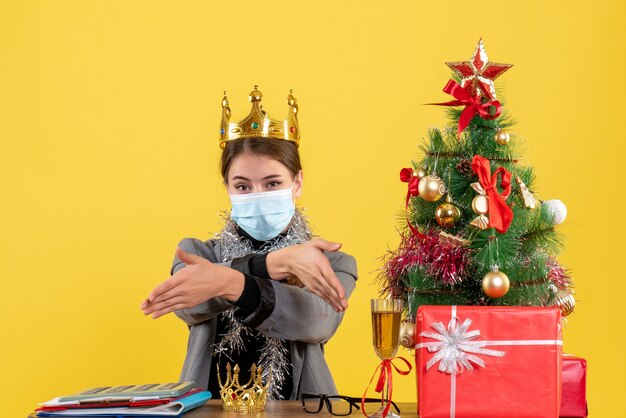 Front view young girl with medical mask wearing crown giving hands xmas tree and gifts cocktail