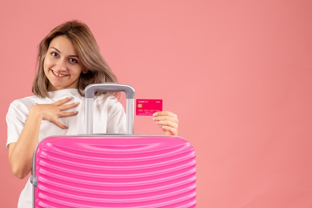 Front view young girl with pink suitcase holding credit card