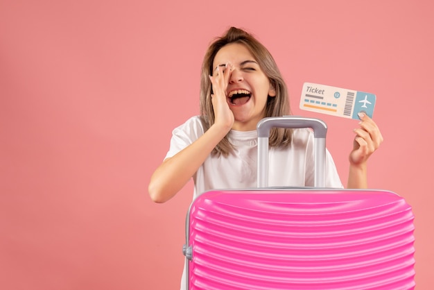 Front view young girl with pink suitcase holding ticket shouting