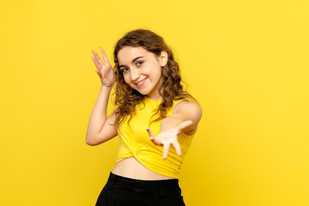 Front view of young girl with smiling expression on yellow wall