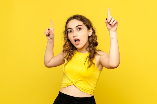 Front view of young girl with surprised expression on yellow wall