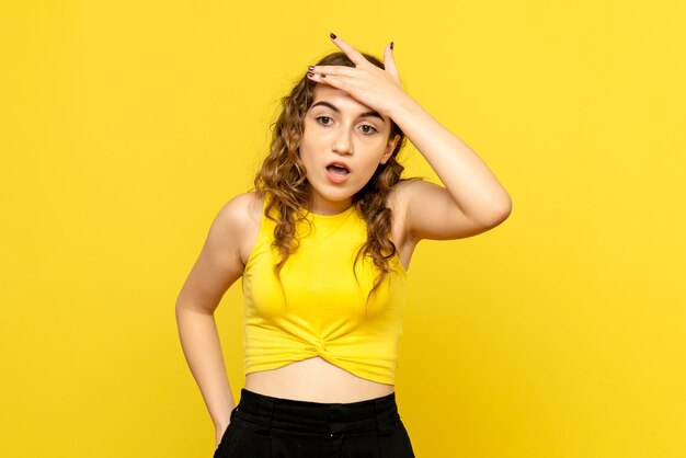 Front view of young girl with surprised expression on yellow wall