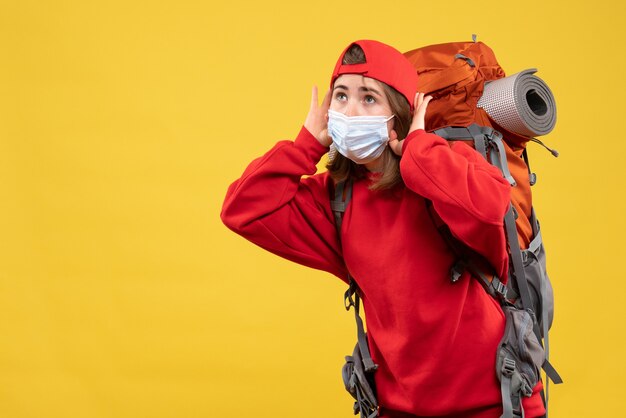 Front view young girl with tourist backpack and mask listening to something