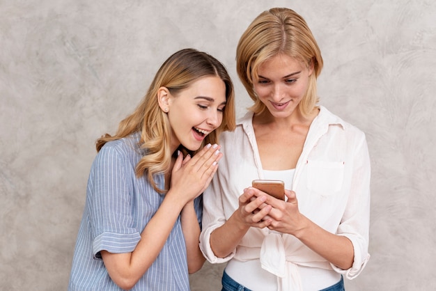 Front view young girls checking mobile phone