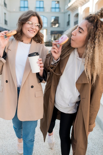 Free photo front view young girls enjoying doughnuts