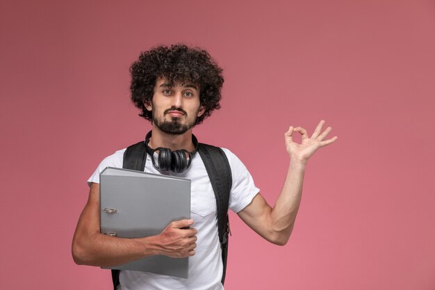 Front view young guy showing ok gesture and holding binder