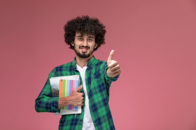 Front view young guy showing thumbs up with different notebooks