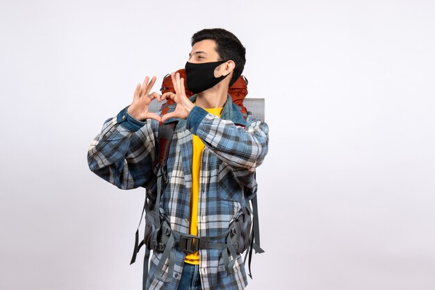 Front view young hiker with backpack and mask making heart sign