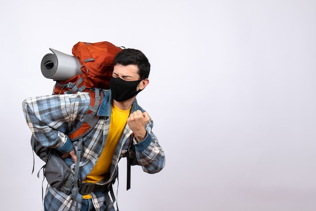 Front view young hiker with backpack and mask putting hand on his back with pain