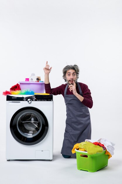 Front view young housekeeper man standing on knee on white wall