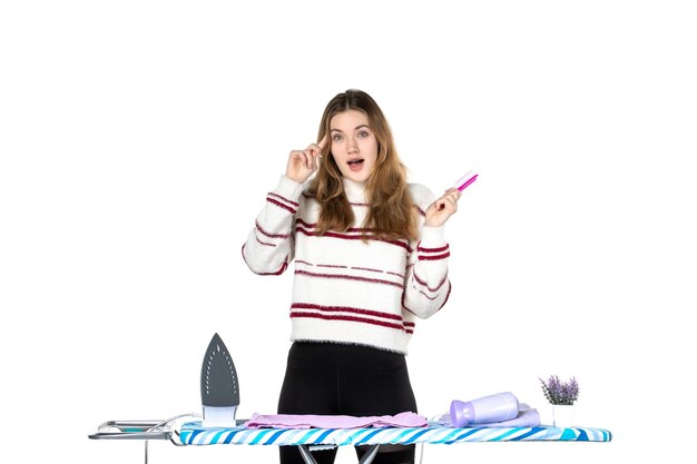 Front view young housewife brushing her hair on white background woman emotion iron home housework beauty