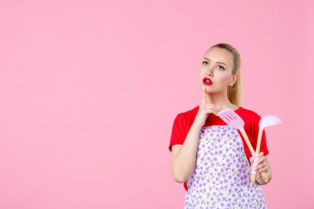 Front view young housewife in cape holding cutlery on pink wall