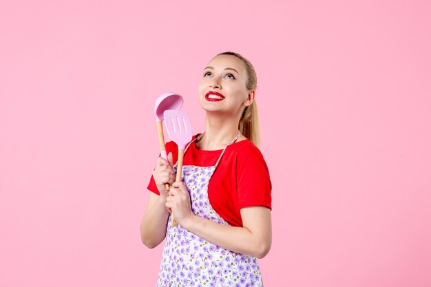 Front view young housewife in cape holding cutlery on pink wall