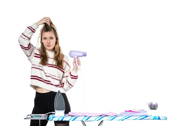 Front view young housewife holding hairdryer on the white